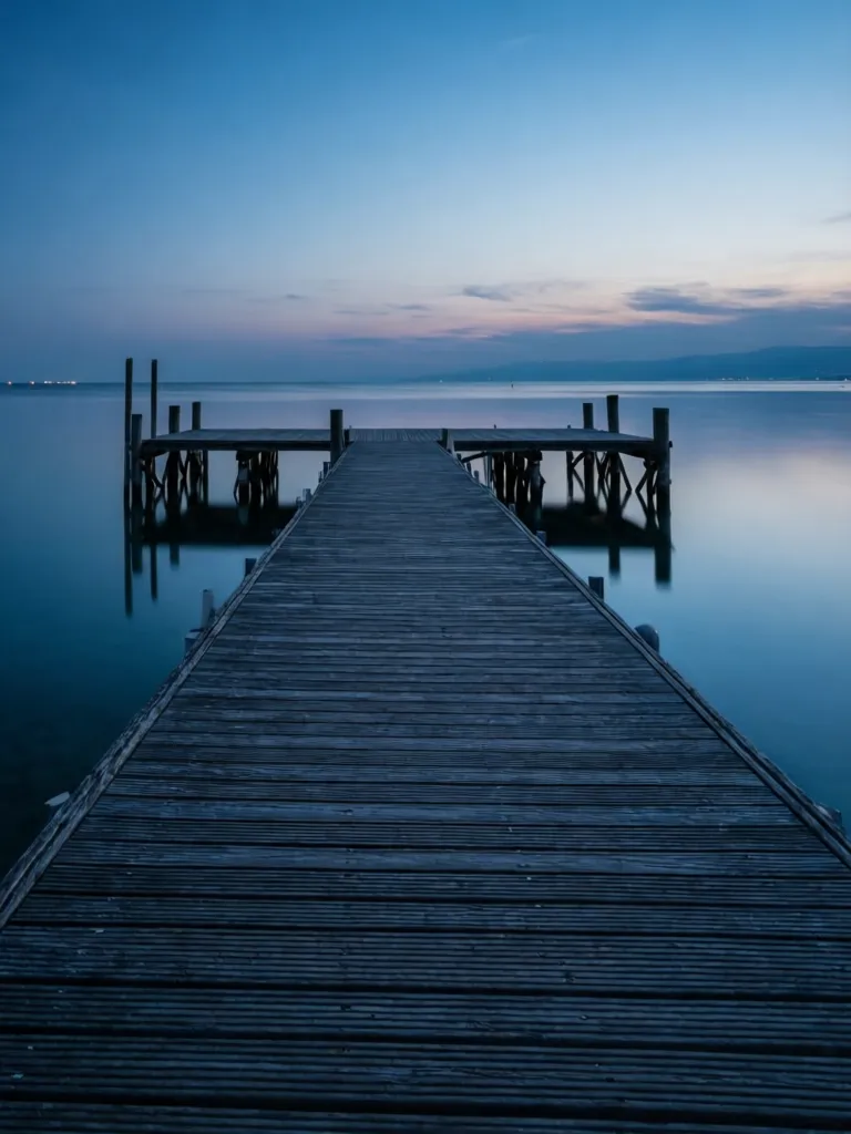 A serene wooden dock at dusk in Pescara, reflecting the blue hour sky.
