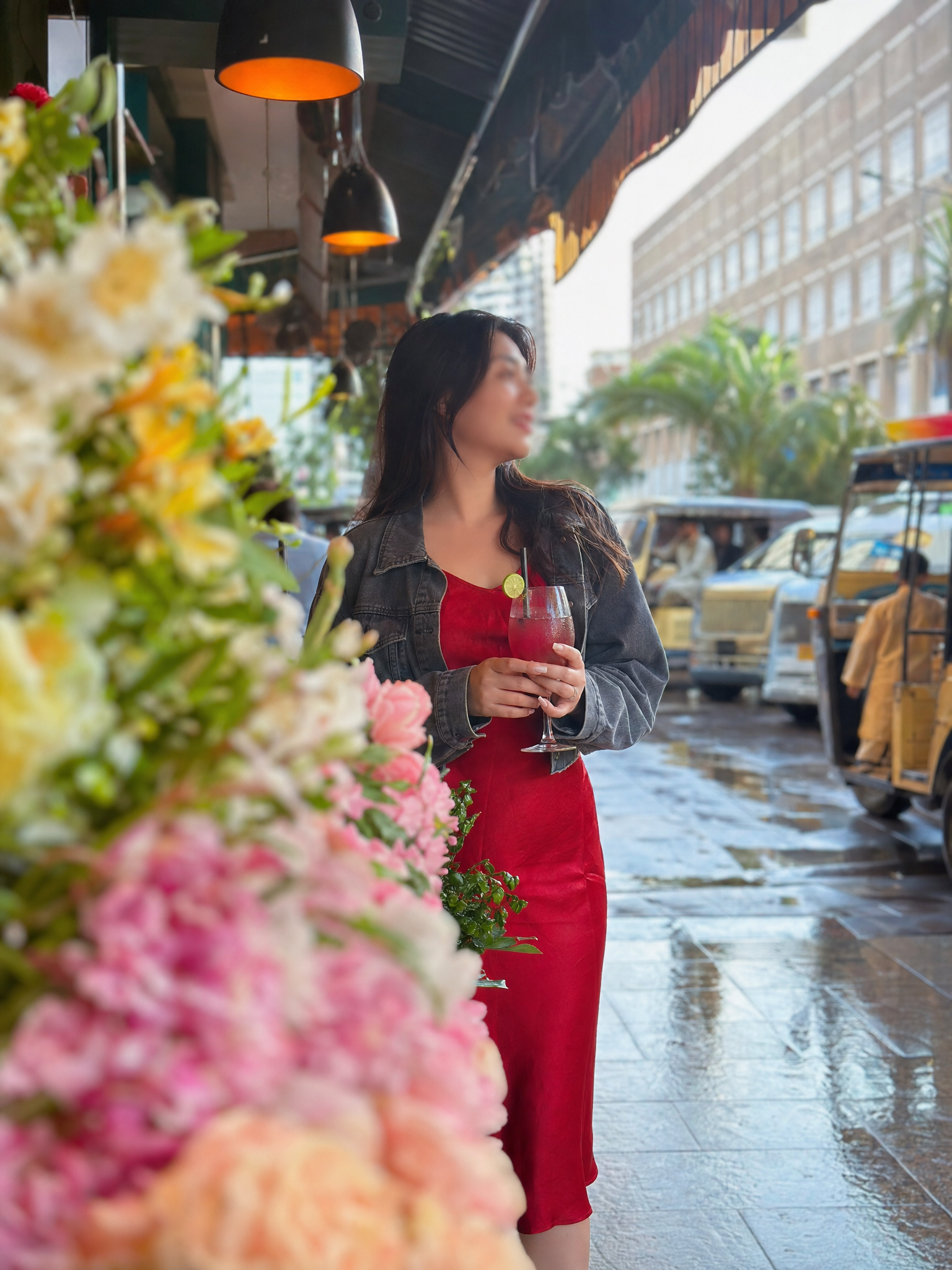 Stylish woman softly blurred behind Karachi flower market blooms, suggesting an attractive profile without clear location context